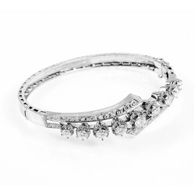 Brazalete esclavo vintage en oro blanco con motivo central en sinuosa fila de limpios y blancos diamantes, talla brillante, en garras de ilusión, flanqueados por bandas de diamantitos 8/8.