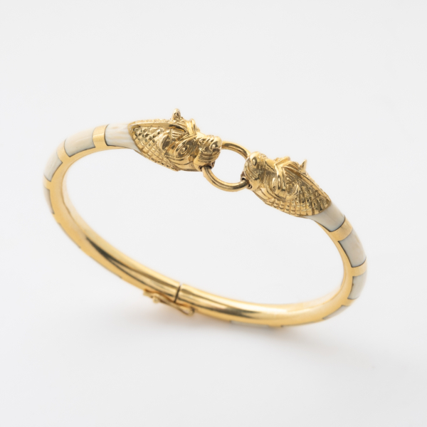 Pulsera esclava en oro y aplicaciones de hueso a tramos alternados con decoraci&oacute;n central de dos cabezas de felino enfrentadas.