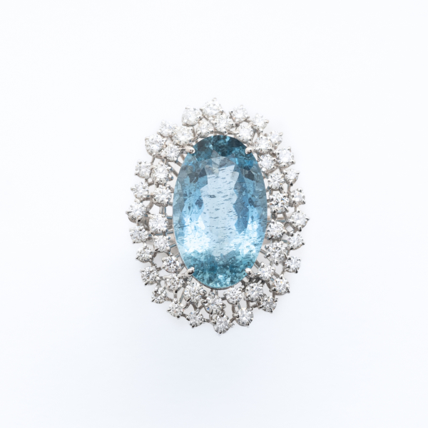 Gran sortija roset&oacute;n en oro blanco con aguamarina talla oval orlada por dos bandas de diamantes talla brillante 
