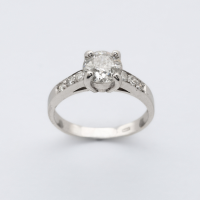Sortija en oro blanco con diamante central talla brillante antigua y brazos de diamantes talla brillante.