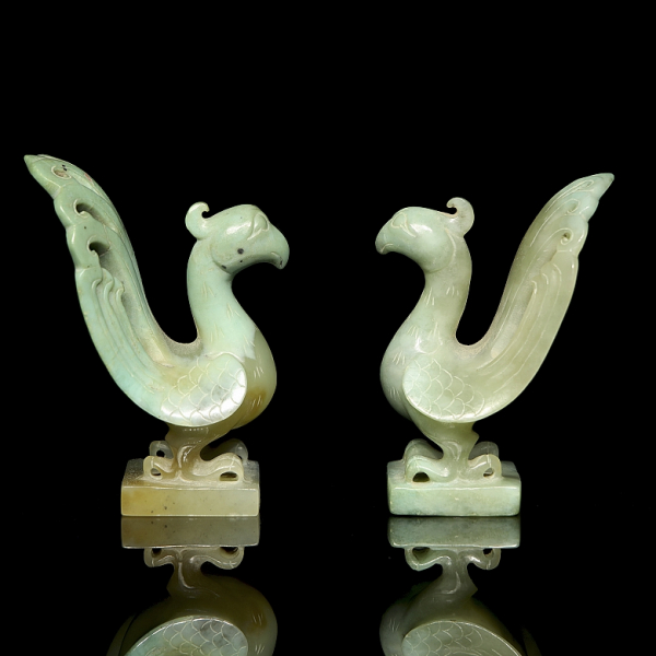 Pareja de figuras de jade “Fénix”, dinastía Han.  Pareja de figuras talladas en jade de tonalidad verde pálido a amarillenta, representando dos aves fénix (fènghuáng) enfrentadas.