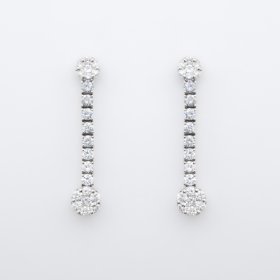 Pendientes largos en oro blanco con dos rosetones unidos por l&iacute;nea de diamantes talla brillante.
