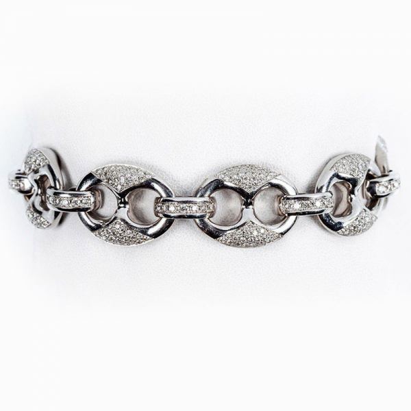 Brazalete de alta joyería en sólida montura de oro blanco, formada por grandes eslabones de calabrote con las vistas cuajadas de limpios y blancos diamantitos, talla brillante