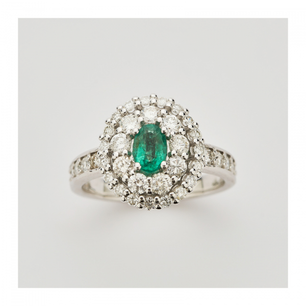 Sortija rosetón en oro blanco y esmeralda central talla oval con doble orla y brazos de diamantes talla brillante.