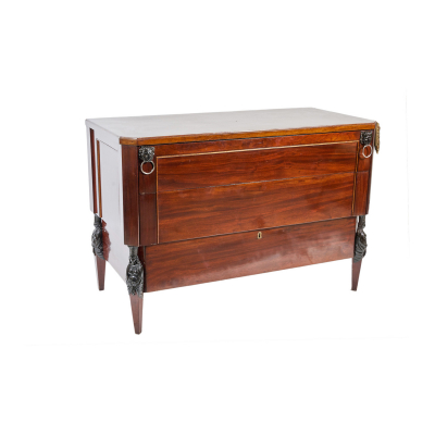 C&oacute;moda estilo Imperio en madera de caoba con decoraci&oacute;n de mascarones en forma de le&oacute;n y cari&aacute;dites tallados en los &aacute;ngulos, fles. del s.XIX-ppios. del s.XX.