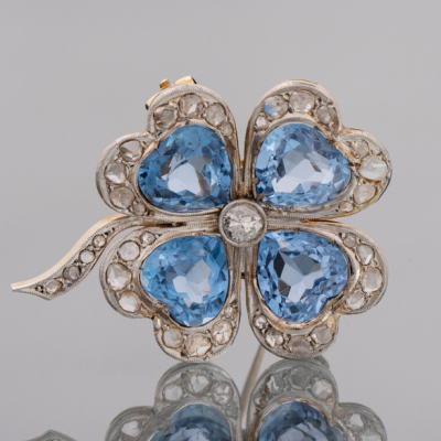 Broche en forma de flor en oro amarillo de 18kt con brillantes talla antigua y topacios azules de talla corazón.