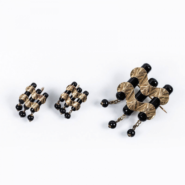 Original conjunto antiguo de alfiler y pendientes, estilo 'decó', de formas ondulantes, que recuerda las olas del mar. Realizado en oro amarillo 18 K y piezas de ónix negro.
