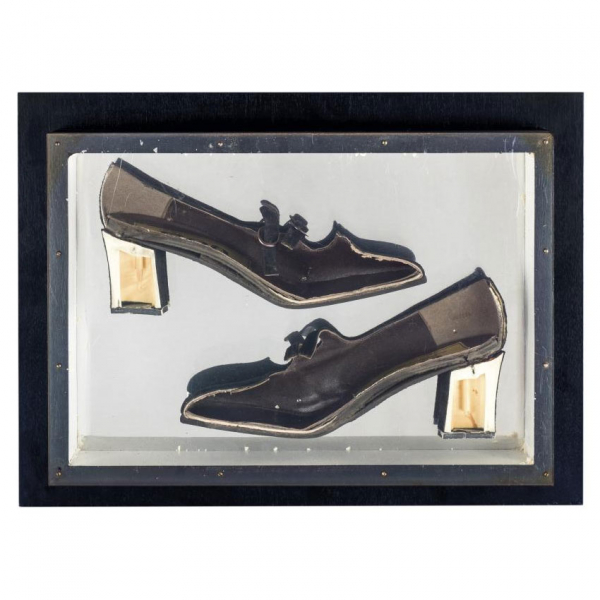 Arman. "Construction of shoes (1965)". Zapato de tacón (coupe) sobre panel de madera negra con cubierta de plexiglás.