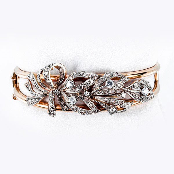 Brazalete esclavo vintage, en sólida montura 'esqueleto' de oro amarillo, con centro en motivo de lazada vegetal