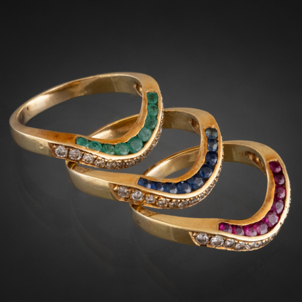Conjunto de tres anillos en oro amarillo de 18kt con brillantes, zafiros, esmeraldas y rubíes calibrados.