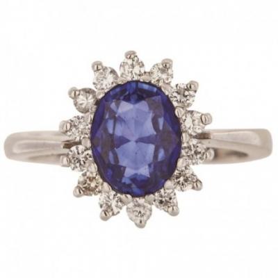 Sortija rosetón en oro blanco con zafiro azul talla oval orlado por diamantes talla brillante. 