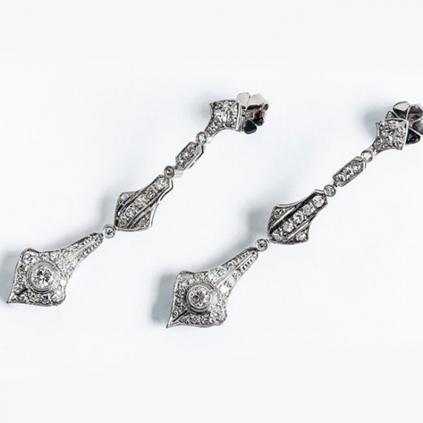 Delicados pendientes largos, estilo art-dec&oacute;, en platino con un limpio y blanco diamante central, talla brillante 