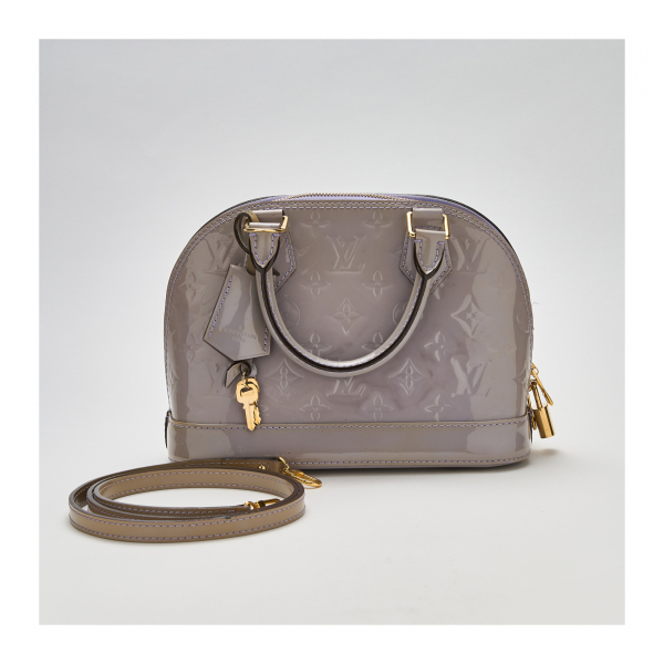 LOUIS VUITTON. Bolso modelo «Alma BB Monogram Vernis» en charol de tonalidad violeta con cierre de cremallera y candado con dos llaves.