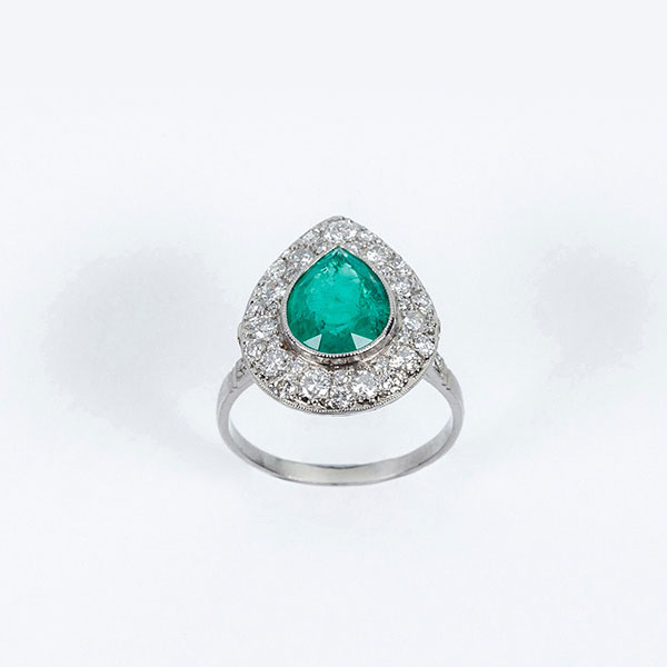 Delicada sortija en platino, con una bella esmeralda colombiana, talla perilla, y orla en pavé de limpios y blancos diamantes 
