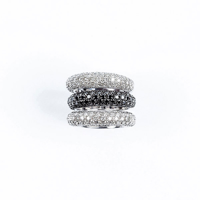 Conjunto de tres anillos de oro blanco en pavé de diamantes, blancos en dos de ellos y negros en el otro.