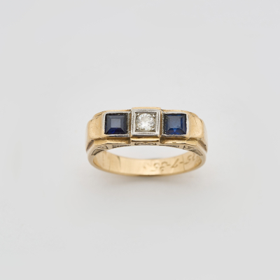 Sortija tresillo en oro y vistas en platino con diamante talla brillante antigua custodiado por s&iacute;miles de zafiro azul talla carr&eacute;. 