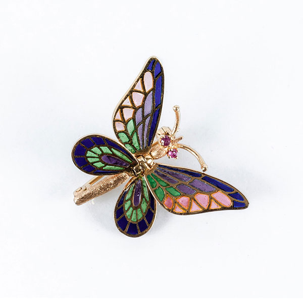 Delicado alfiler en forma de mariposa, con las cuatro alas articuladas independientemente y decoradas con esmaltes transparentes multicolor y rubíes en los ojitos.