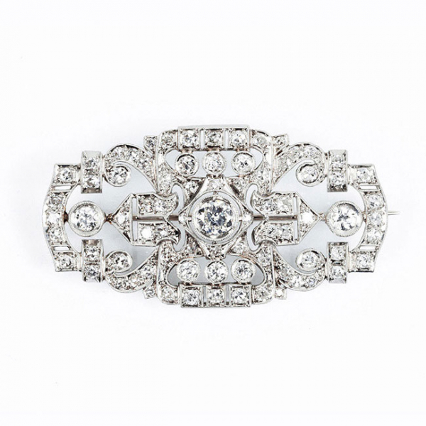 Bello alfiler antiguo, estilo &#039;art-decó&#039;, en sólida montura de oro blanco 18 K, en plaqueta semi-oval, con un limpio y blanco diamante central 