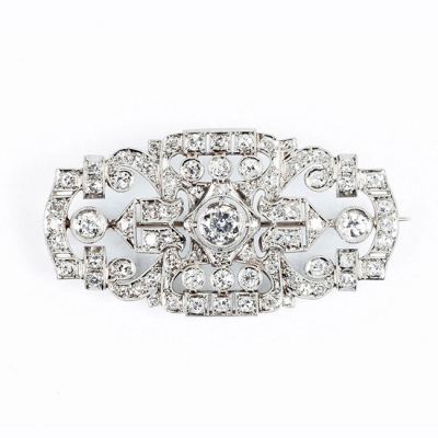 Bello alfiler antiguo, estilo &#039;art-decó&#039;, en sólida montura de oro blanco 18 K, en plaqueta semi-oval, con un limpio y blanco diamante central 