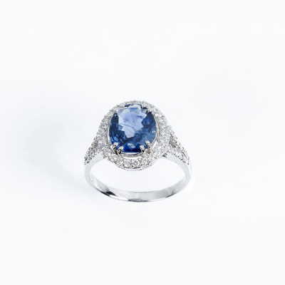 Sortija en oro blanco con un bello zafiro azul de Ceylán, oval, sobre orla y hombros en filas de limpios y blancos diamantes, talla brillante