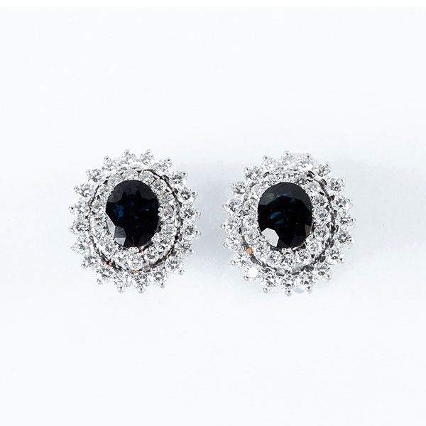 Elegantes pendientes de alta joyería, años 90, en oro blanco 18 K, con zafiro fino azul, talla oval y doble orla de limpios y blancos diamantes 