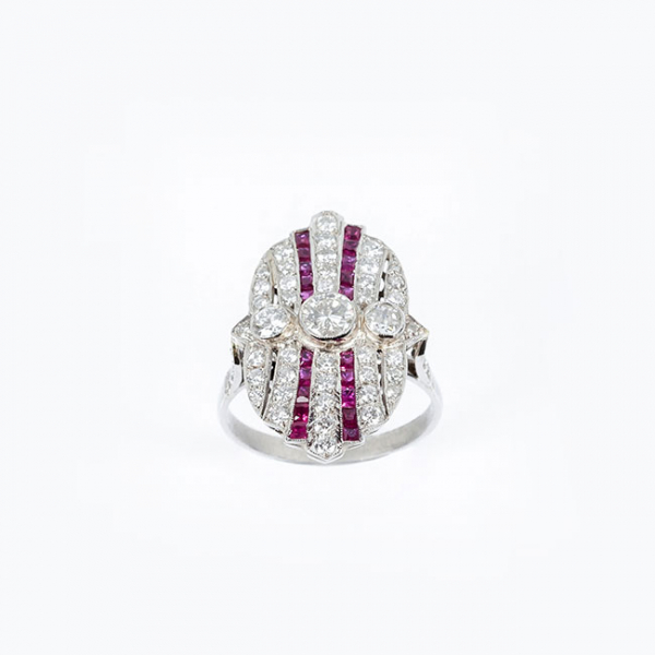 Sortija lanzadera oval, estilo art-dec&oacute; en platino con un limpio y blanco diamante central, talla brillante y bandas de limpios y blancos diamantitos, talla brillante y de rub&iacute;es 