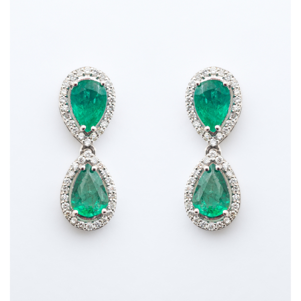Pendientes largos en oro blanco con dos esmeraldas talla perilla orladas por diamantes talla brillante.