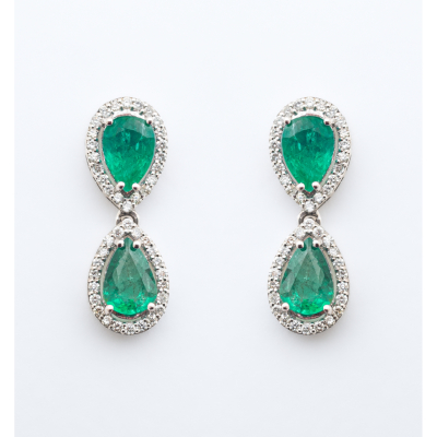 Pendientes largos en oro blanco con dos esmeraldas talla perilla orladas por diamantes talla brillante.