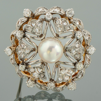 Broche en forma de flor con perla cultivada central orlado de brillantes.