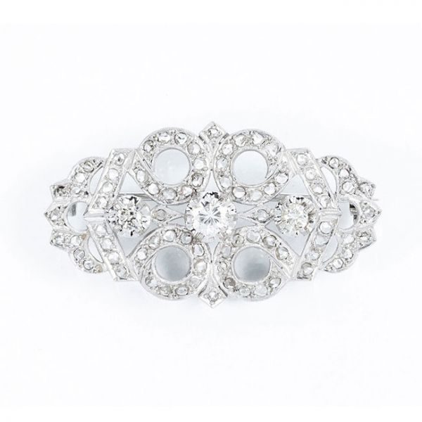 Delicado alfiler vintage en montura calada de platino u oro blanco, con tres centros de diamante 