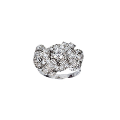 Sortija vintage, en montura calada de oro blanco, con un limpio y blanco diamante talla brillante, central en garras de ilusión, orlado de bandas onduladas de diamantes talla brillante, formando una doble lazada.