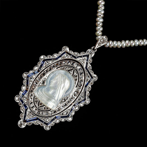 Bello colgante oval 'art-decó' en montura de oro amarillo 18 K y vistas de platino, con relieve en nácar de la Virgen María