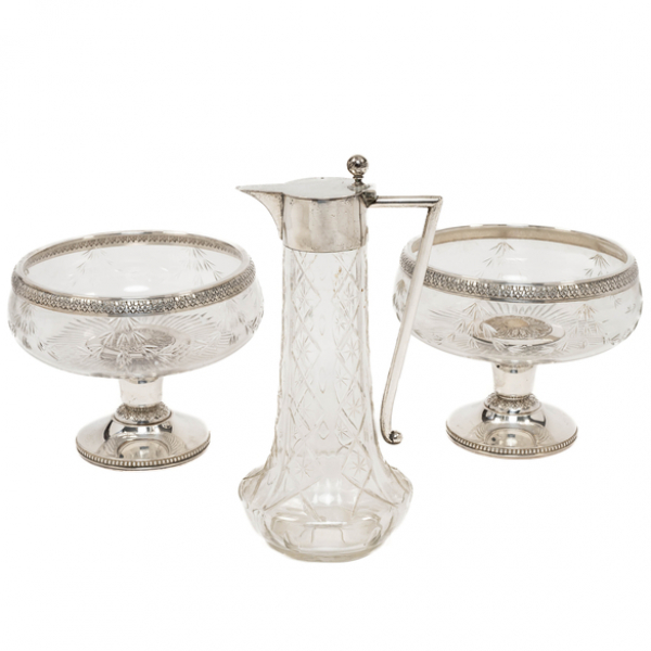 Conjunto de dos fruteros y jarra de agua en cristal tallado con montura en plata española y punzonada del siglo XX.