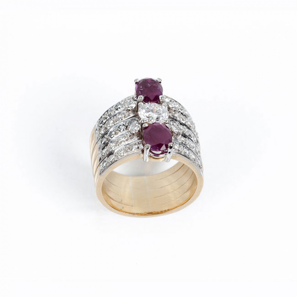 Espléndida sortija años 80, en sólida montura de oro amarillo 18 K, con un limpio y blanco diamante, talla brillante, central, flanqueado de dos rubíes finos talla oval