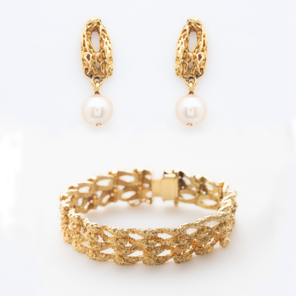 Pendientes con perla cultivada de 6,5 mm. y brazalete articulado en oro mate y brillo que presenta un patr&oacute;n entrelazado y calado de acabado texturizado.