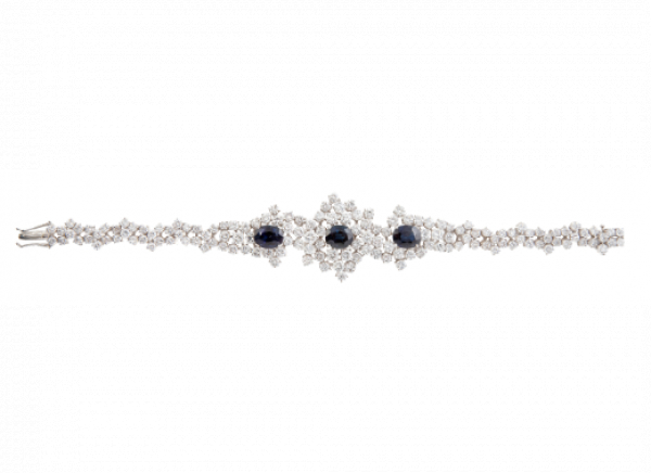 Brazalete de brillantes con tres zafiros centrales de talla oval. Con diseño que aumenta de tamaño hacia la parte central, realizado con brillantes engastados en garras a diferentes alturas. En oro blanco de 18K.
