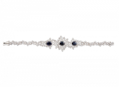 Brazalete de brillantes con tres zafiros centrales de talla oval. Con diseño que aumenta de tamaño hacia la parte central, realizado con brillantes engastados en garras a diferentes alturas. En oro blanco de 18K.
