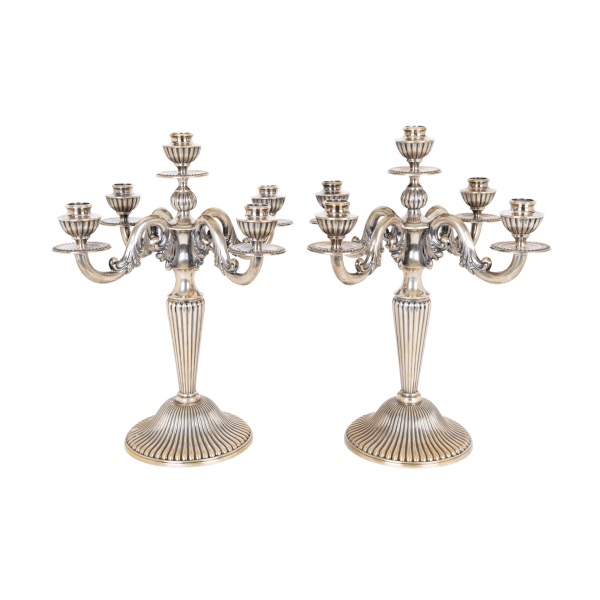 Pareja de candelabros de cinco luces en plata espa&ntilde;ola punzonada con decoraci&oacute;n de gallones y motivos vegetales, c.1940.