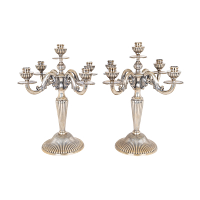 Pareja de candelabros de cinco luces en plata espa&ntilde;ola punzonada con decoraci&oacute;n de gallones y motivos vegetales, c.1940.