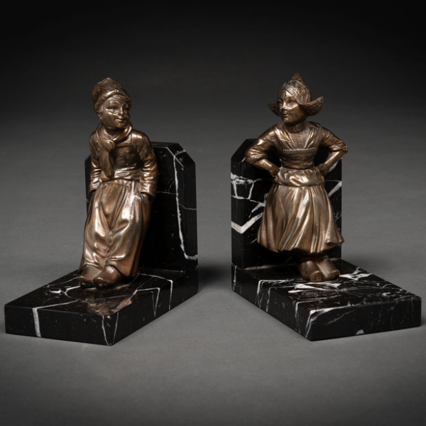 Sujeta libros realizados en m&aacute;rmol y figuras holandesas en calamina como tenantes. h. 1930