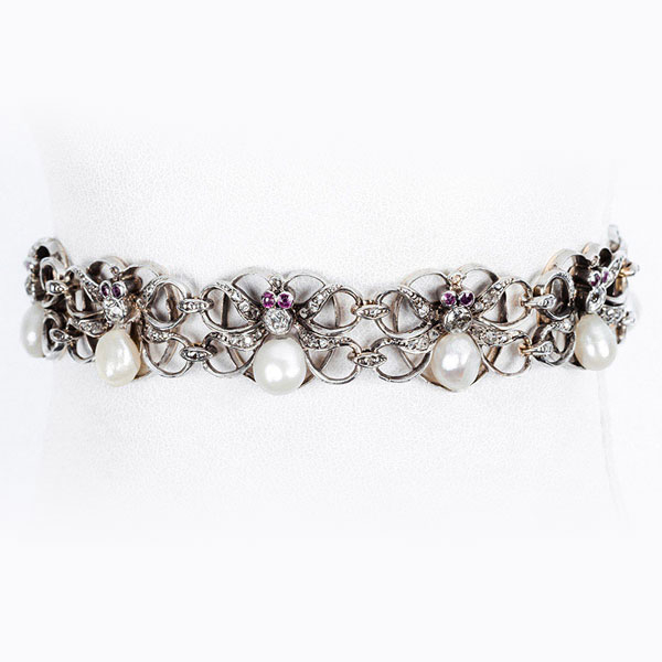 Pulsera antigua en oro amarillo, formada por eslabones en lazada doble calada, con centro de diamante talla antigua, diamantitos, rub&iacute;es y perlitas en forma de pera