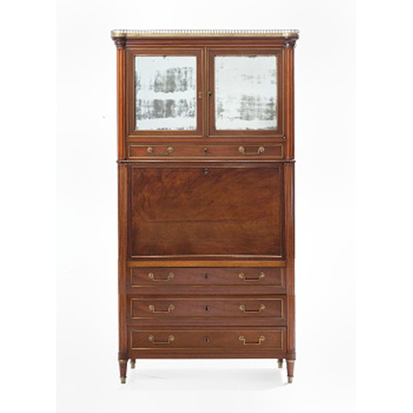 Mueble secreter abattant en madera de caoba con molduras en metal. Interior con cajones y diferentes departamentos. Parte inferior con 3 cajones y parte superior con puertas de espejo. Remates y barandilla en metal. Estilo Luis XVI.