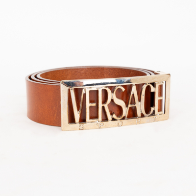 VERSACE SPORT. Cintur&oacute;n en cuero de tonalidad marr&oacute;n camel con cierre con logotipo en metal dorado.  