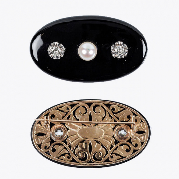 Alfiler antiguo formado por placa oval de ónix negro sobre oro amarillo 18 K, con celosía calada y dos centros de blancos diamantes