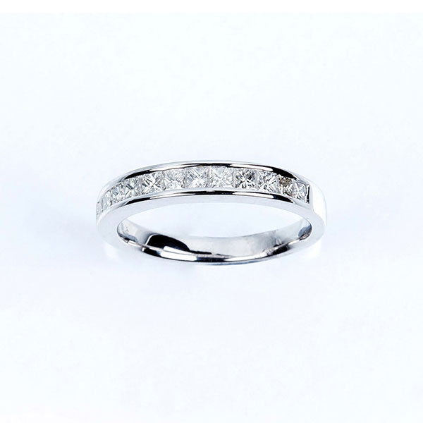 Anillo media alianza en oro blanco 18 K, con banda de limpios y blancos diamantes talla princesa.