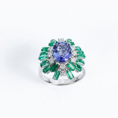 Sortija en oro blanco con una bella tanzanita oval orlada de limpios y blancos diamantes, talla brillante y bonitas esmeraldas 