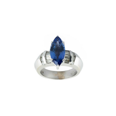 Sortija en sólida montura de oro blanco 14 K con una bella tanzanita talla marquisse flanqueada de bandas limpios y blancos diamantes, talla brillante y baguette