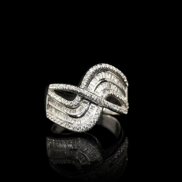 Anillo de oro blanco de 18 kt con diseño entrelazado y diamantes talla baguette y talla brillante.